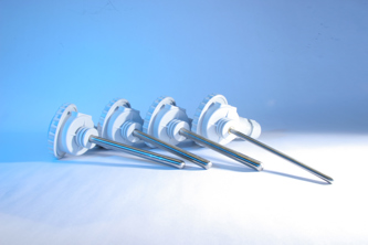 Four white industrial probe-style sensors with long, slender metal rods laid out in a row on a light surface.