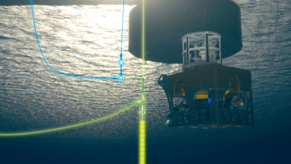 Underwater view of a subsea structure suspended beneath a floating platform, with a metal frame enclosing equipment and cables. 