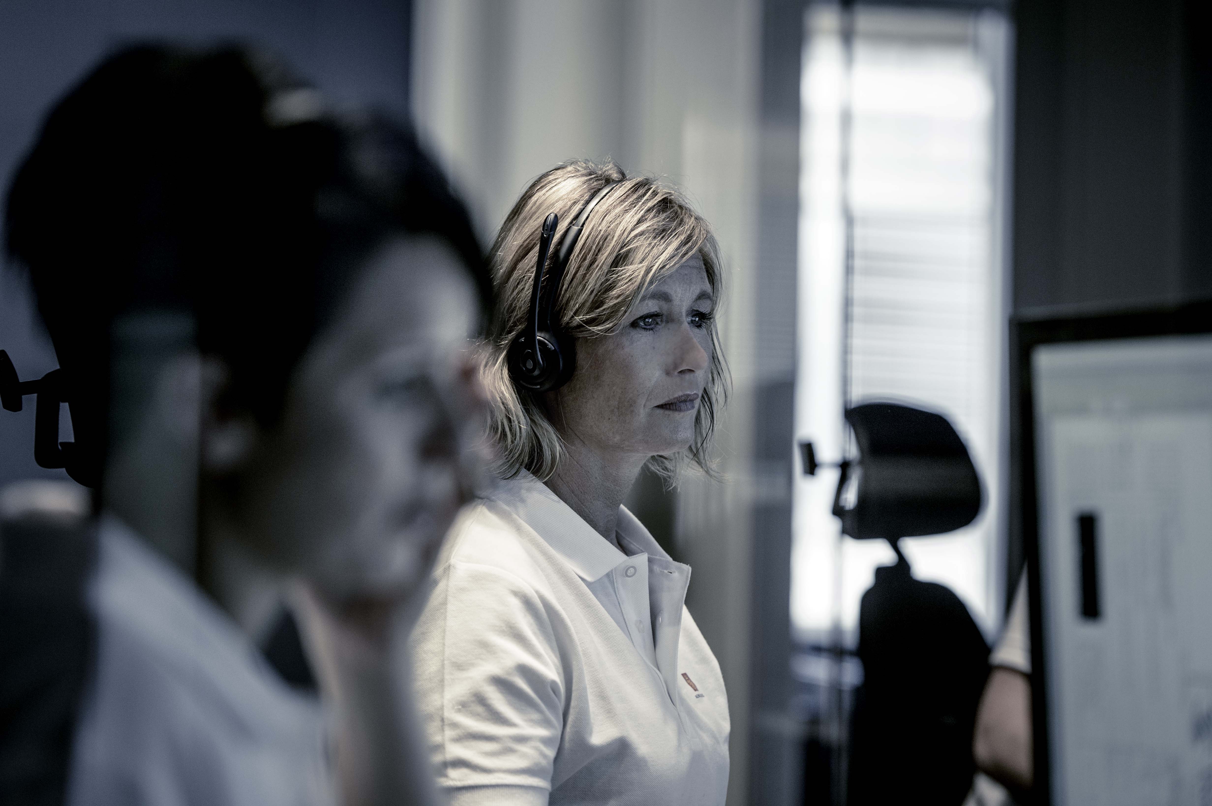 Two 24/7 Kongsberg Maritime call operators, handling customer calls in front of large desk computer screens