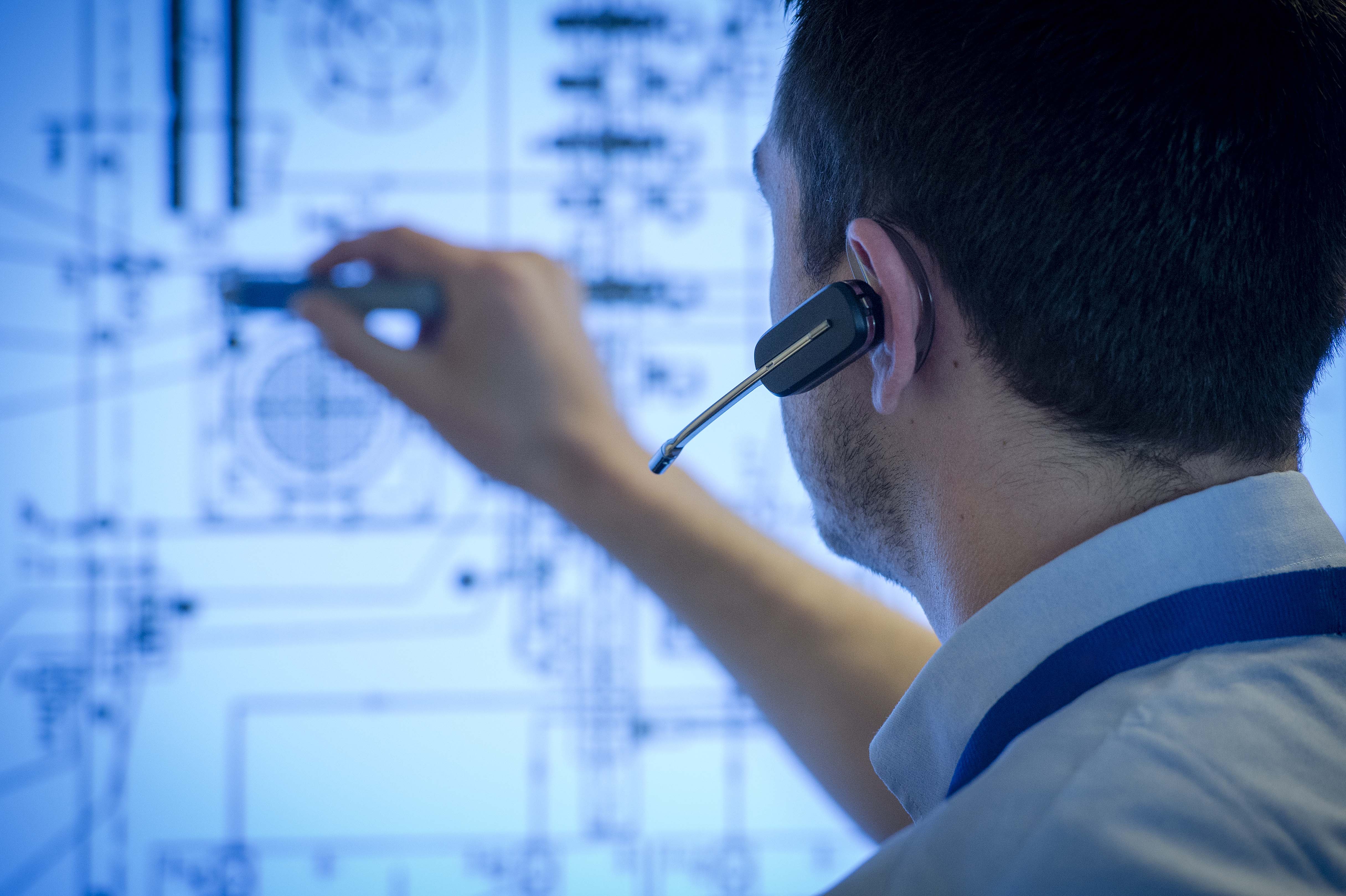Engineer interacting with a large touch-enabled projected screen showing a detail system drawing