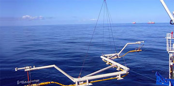 Offshore loading system with articulated transfer arms and flexible hoses being lifted above a calm sea