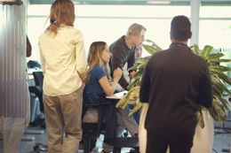 Students at a desk in a bright office, working side by side at laptop computers. 